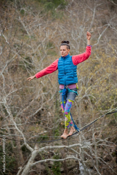 Obraz A tightrope walker walks along a cable stretched over a canyon.