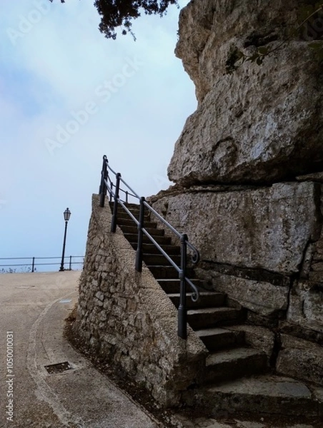 Fototapeta Ancient stairway to Erice castle. Stairs made of stone. Medival architecture. Historical city in sky. Town in Sicily surrounded by clouds. Foggy weather in summer. Italian travel destination.