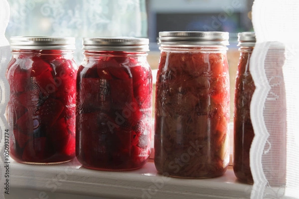 Fototapeta Homemade canned beets and rhubarb on a window sill; colorful display of old-fashioned food preserves