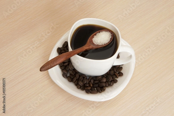 Fototapeta Cup of coffee on a table with a wooden spoon and sugar