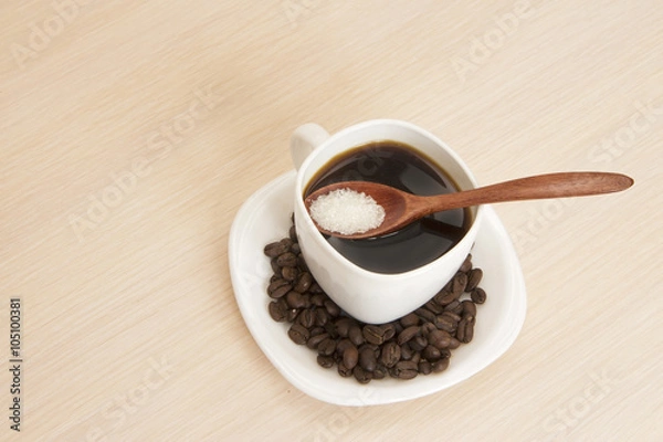 Fototapeta Cup of coffee on a table with a wooden spoon and sugar