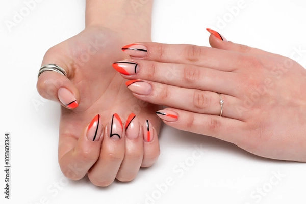 Fototapeta Orange abstraction and black stripes on long sharp nails close-up on white background.	