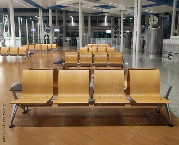 Fototapeta Airport waiting area with organized wooden benches and digital displays at night