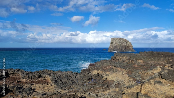 Fototapeta Rocky shore and ocean with prominent rock formations under a blue sky. Madeira, Portugal, Cais do Porto da Cruz