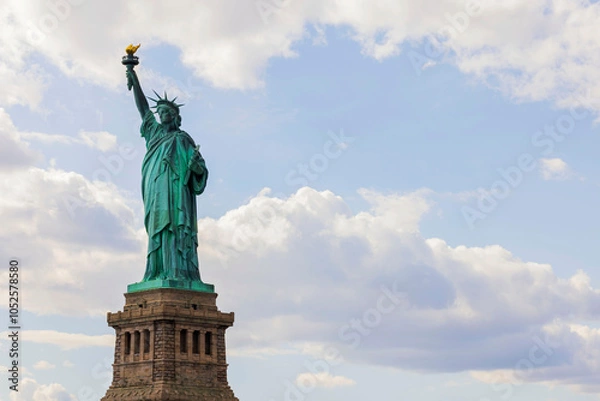 Fototapeta Iconic Statue of Liberty against a partly cloudy sky, symbolizing freedom and welcoming visitors to New York City.