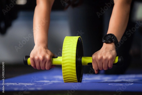Fototapeta woman doing abdominal exercise with wheel. Home Workout Exercise to Lose Weight