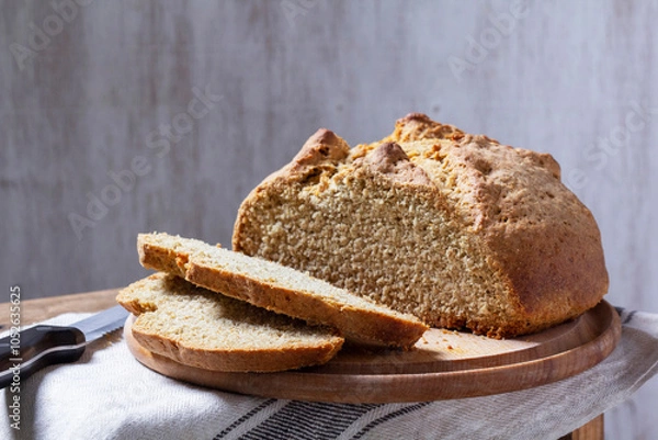 Fototapeta Homemade Irish soda bread cut into pieces and knife on wooden background.