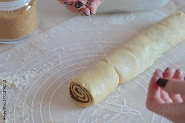 Obraz Close-up a woman hands cuts a twisted dough with a thread on a table on a silicone mat