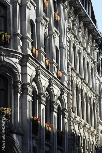 Fototapeta Colonial historic residential stone architecture with flowers and vines on window sill on sunny day