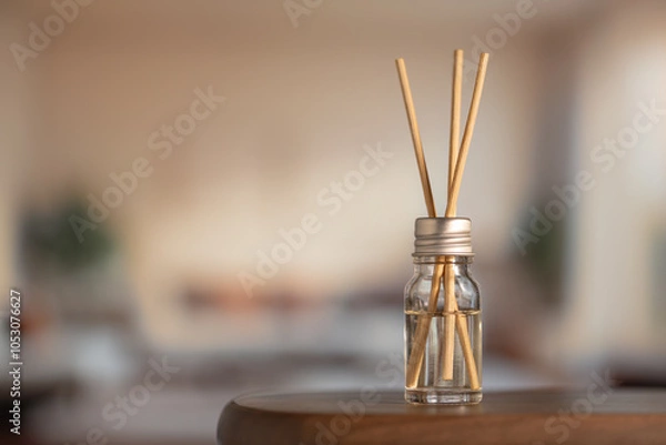 Fototapeta Aromatic air freshener close-up. Aroma sticks in glass bottle on table in room, home comfort concept, high resolution.