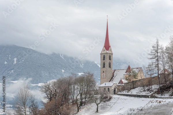 Fototapeta Chiesa innevata in un paese alpino