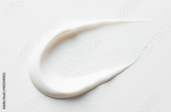Fototapeta A wide short smear of white cream on a smooth white surface, top view.