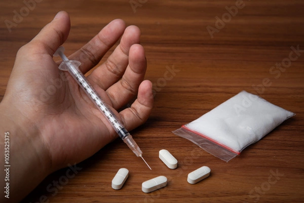 Fototapeta hand trying to reach and use drugs on white table with wooden, methamphetamine, and pills. The concept for drugs addiction, International Day against Drug Abuse. say no to drugs