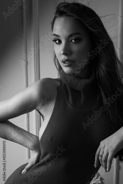 Obraz In this captivating black and white photograph, a long-haired brunette model flaunts her figure in a chic, fitted design. The studio's clean lines and subdued tones