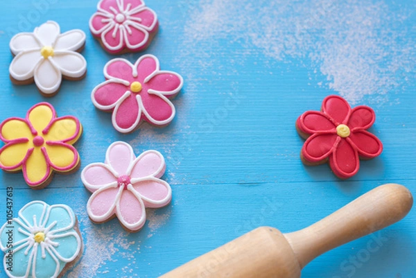 Fototapeta Happy Easter  (home-baked cookies) 
Flower shaped gingerbread cookies and rolling pin on a blue wooden table.
