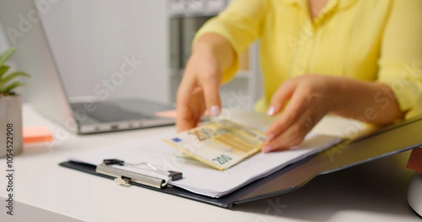 Fototapeta Woman opening the clipboard and raising a pile of money. Accountant taking money out of a clipboard.