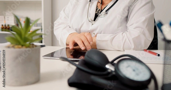 Fototapeta Woman doctor using technology to consult people remotely on tablet. Medical worker answering to patients online.