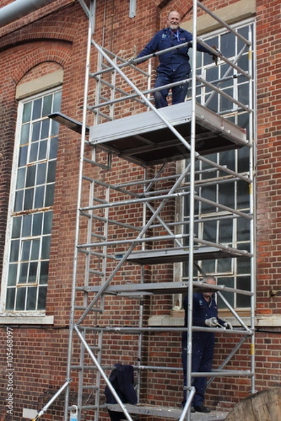 Fototapeta Two painter and decorators working from a scaffold tower