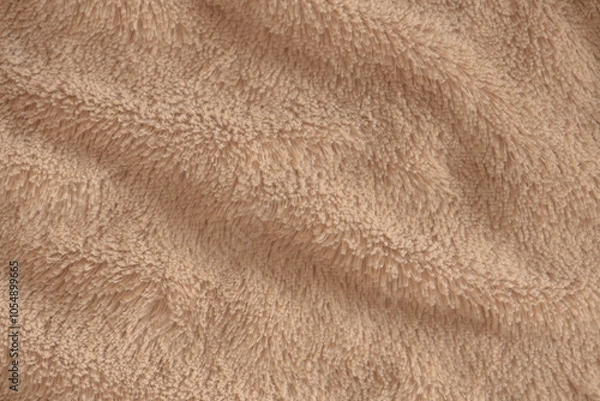 Fototapeta Beige delicate soft background of plush fabric. Texture of soft faux fur blanket textile with beautiful folds, close-up, high resolution.