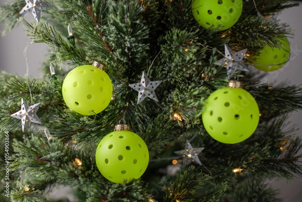 Obraz Close view of a Christmas tree decorated with pickleballs as ornaments and shining lights and stars. Selective focus. Pickleball Christmas tree backdrop.