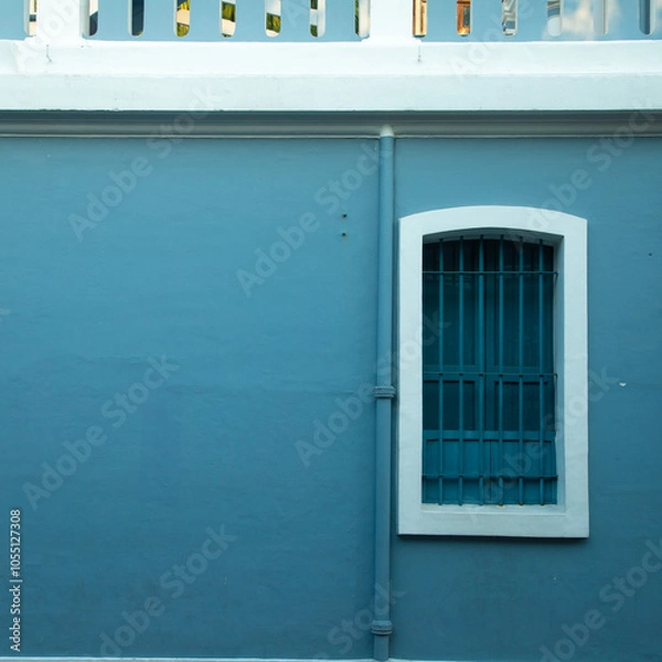Fototapeta Blue iron and wooden color window with blue color concrete wall on the side of tree shadow, white town building concrete walls for photo shoot