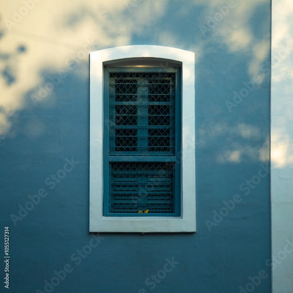 Fototapeta Blue iron and wooden color window with blue color concrete wall on the side of tree shadow, white town building concrete walls for photo shoot