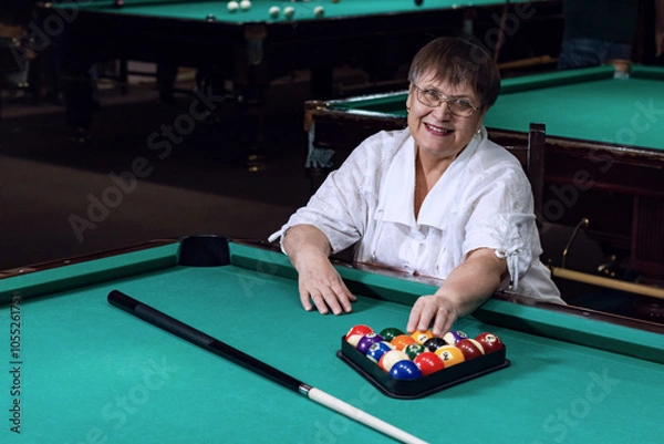 Obraz An elderly woman plays billiards in a billiard club.