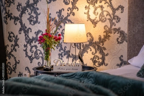 Fototapeta Bed side lamp and red flowers with a white sign saying "Dream follow your dream"
