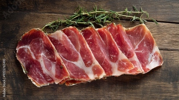 Fototapeta Herb infused jamon on a textured wooden background featuring slices of delicately colored pink jamon