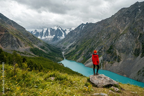 Fototapeta A tourist girl stands on a stone overlooking the beautiful mountains and Lake Shavlinskoye. Altai. Siberia