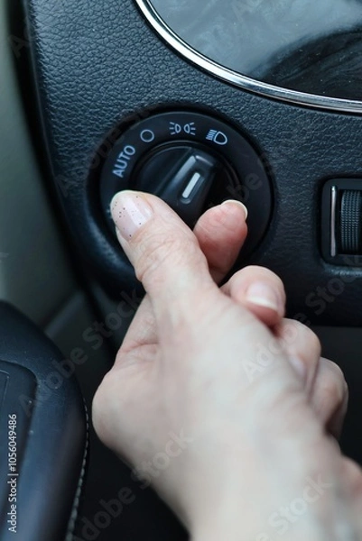 Obraz Low beam headlights - hand turning on the lights in the car