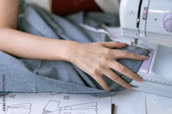 Fototapeta Close up fashion designer hand using sewing machine making clothes in a workshop studio. SME small business owner or retail store concept