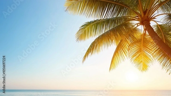 Fototapeta Palm tree is in the foreground of a beautiful blue ocean. The sky is clear and the sun is shining brightly