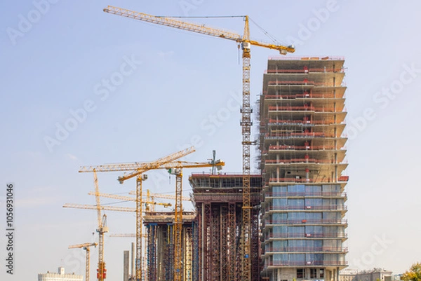 Fototapeta A Modern Construction Site Featuring Cranes Operating Against a Beautiful, Clear Blue Sky