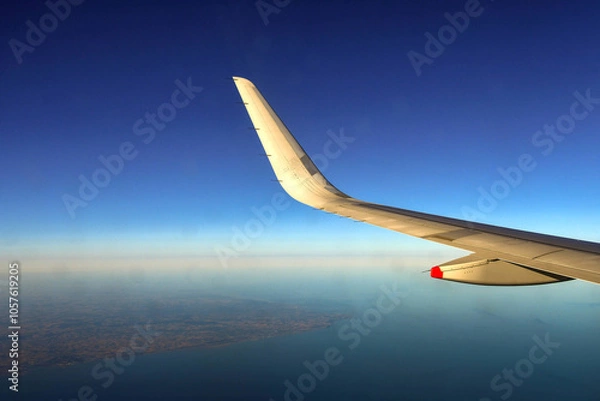 Fototapeta Wing and curved wingtip of a holiday jet in flight against a deep blue sky. Copy space.