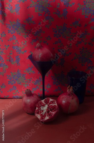 Fototapeta Still life with pomegranates on red vintage background with blue glasses lifestyle fall composition