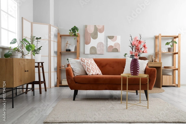 Fototapeta Interior of living room with sofa and magnolia flowers in vase on coffee table