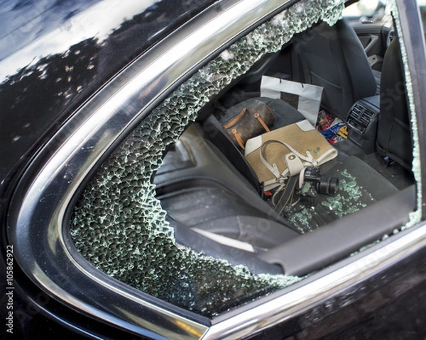 Fototapeta Smashed car window being used to rob a camera and handbag