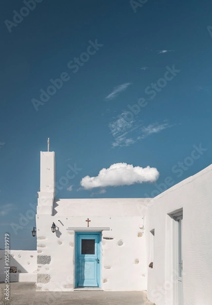 Obraz A charming Cycladic house in Greece showcases its distinctive white architecture and a vibrant blue door against a stunning clear sky with a single cloud drifting by.