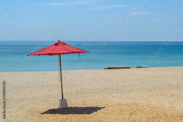 Fototapeta red umbrella on the beach with blue sky background