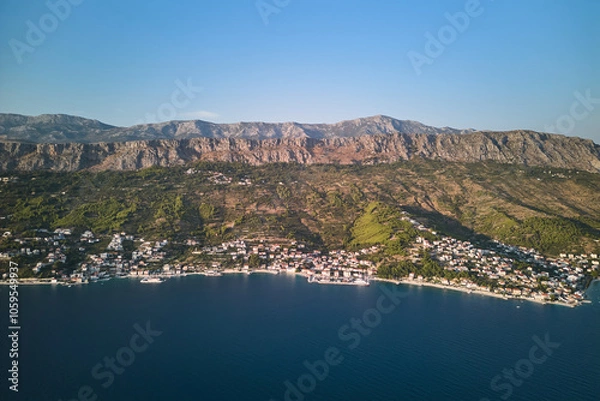 Fototapeta Aerial view of the Adriatic Sea coastline with small villages at the foot of the mountain range in Croatia