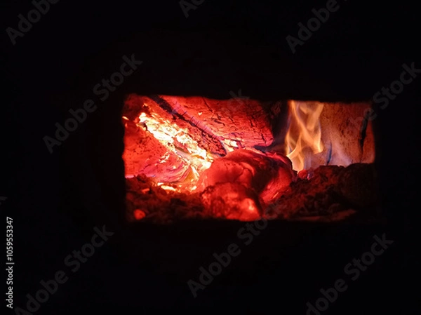 Obraz Wood burning in the dark, a small fire . Gas and wood burning stoves in the village are dangerous . Gas and wood are burned together in the stove.
