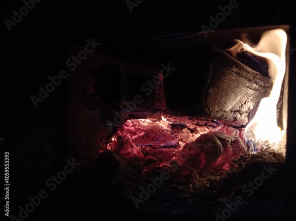 Obraz Wood burning in the dark, a small fire . Gas and wood burning stoves in the village are dangerous . Gas and wood are burned together in the stove.