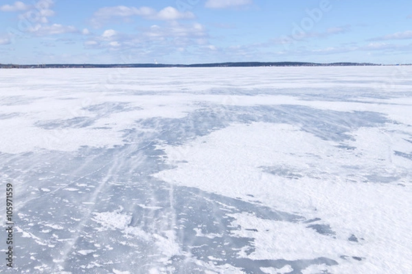 Fototapeta The surface of the lake covered with ice and blizzard