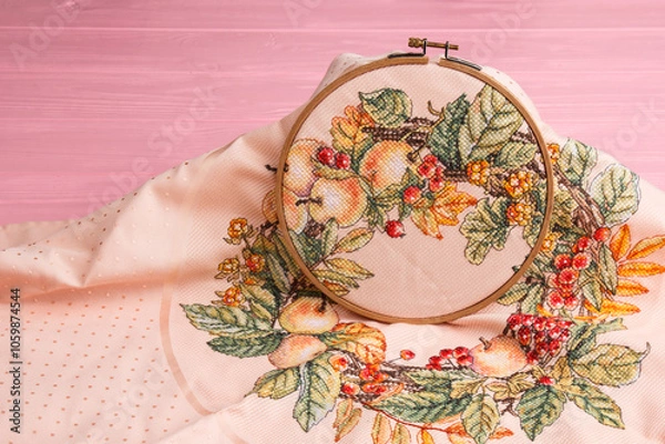 Fototapeta An embroidery hoop with a bright floral pattern is shot close-up against a pale pink background. Do-it-yourself aesthetic installation.