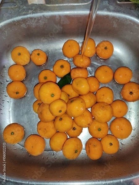 Obraz Ripe tangerines lie in metal sink..
