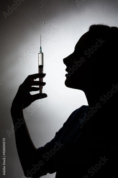 Obraz Silhouette of a girl with a syringe on a gray background.