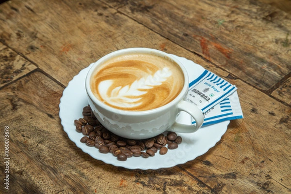 Fototapeta cappuccino cafes in a white cup with leaf shaped and brown colored along with chocolate dips and sugar packets