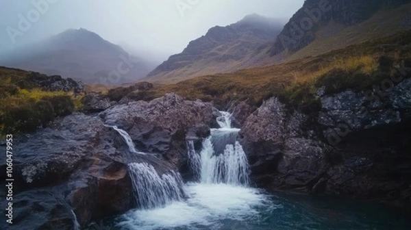 Fototapeta Waterfall in the Fairy Pools, Glen Brittle, Isle of Skye, Scotland, UK. On a gray day in the fall you see the water flowing along the rocks with in the background the famous mountain with the crack in