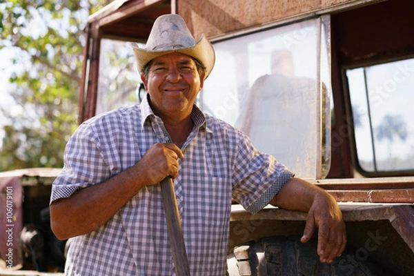 Obraz Portrait Happy Man Farmer Leaning On Tractor Looking At Camera